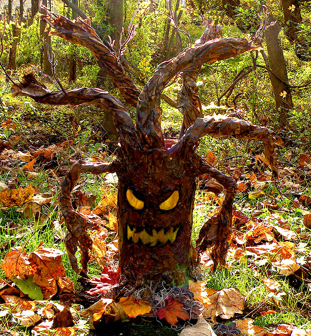 Cardboard and paper spooky tree with creepy face in the woods with fall leaves
