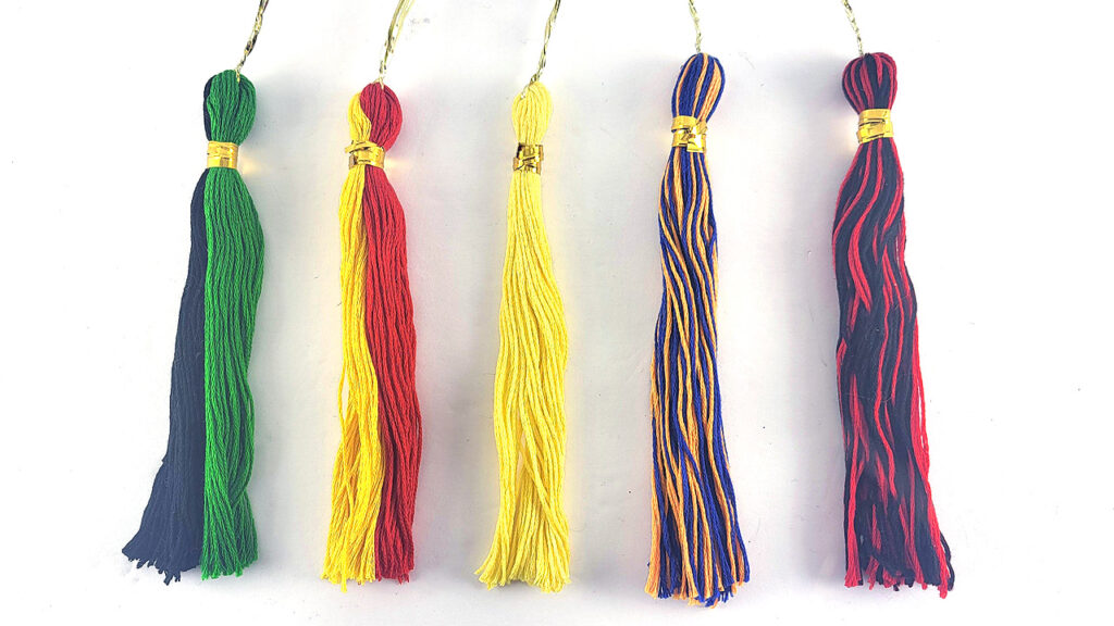 Five handmade graduation tassels in multiple colors including blue, green, yellow, red, and mixed combinations.