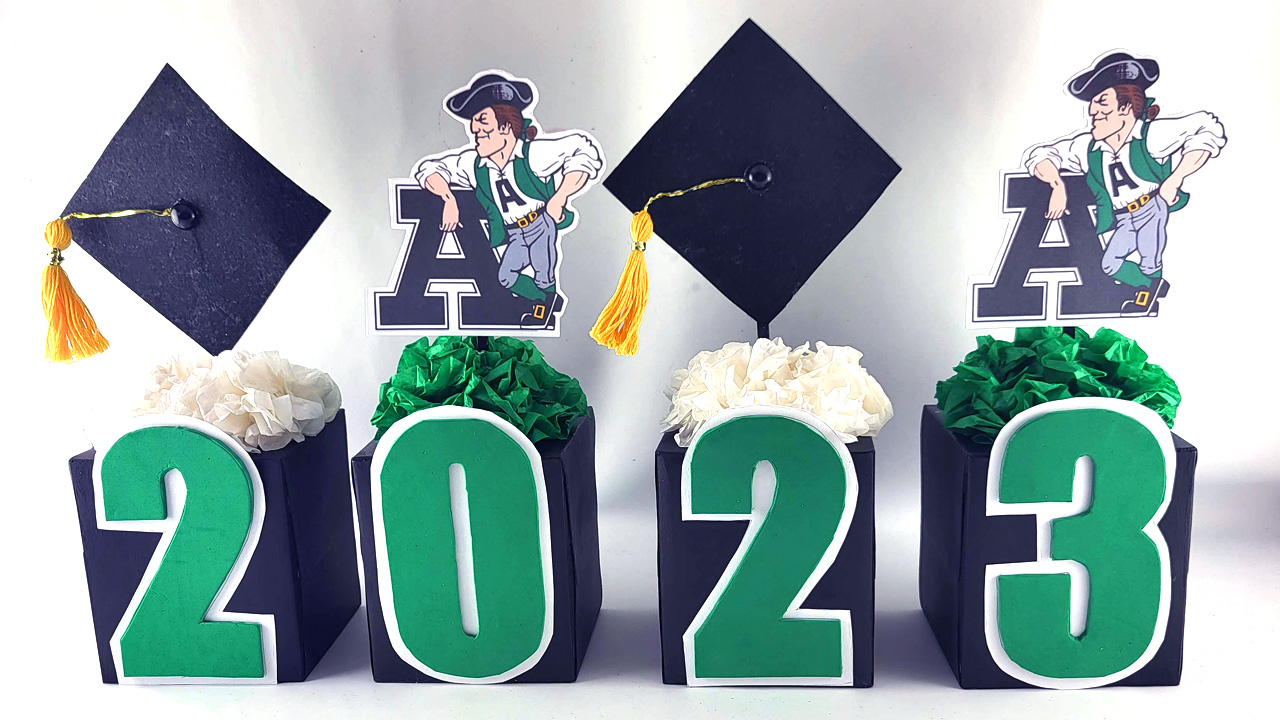 Graduation Centerpiece with 2023 on black cube boxes decorated with numbers, graduation cap, school mascot and tissue flowers