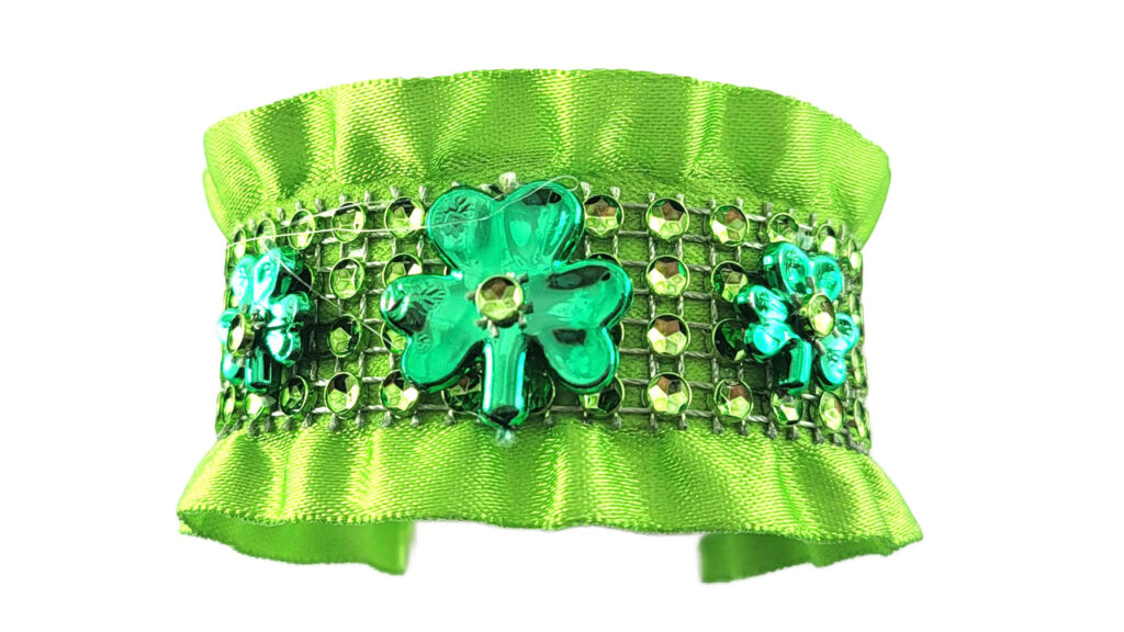 A high-end DIY St. Patrick's Day ruffled bracelet made from lime green satin ribbon and gold rhinestone mesh. It features three decorative green shamrocks with center jewels, showcasing an original boutique-style design.