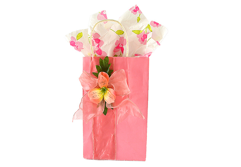 Boutique-style DIY pink gift bag decorated with a delicate floral bow and floral tissue paper, perfect for Mother's Day gifting.
