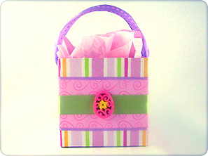 Boutique-style DIY gift basket made from cardstock, decorated with pink and green striped paper, satin ribbon, and a floral egg embellishment.