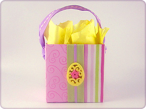 Boutique-style DIY gift box for spring celebrations, decorated with pink and green striped paper, satin ribbon, and a custom decorative egg embellishment.