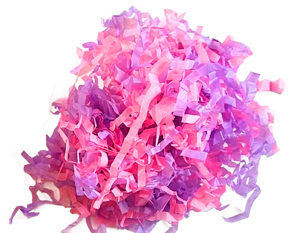 Boutique-style DIY shredded paper filler for gift baskets, created from reused pink and purple tissue paper for a high-end look.