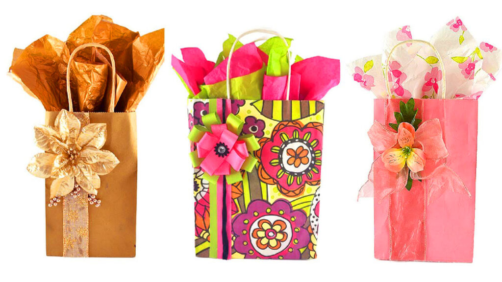 Three boutique-style DIY gift bags featuring professional tissue paper bouquets and handmade floral ribbon embellishments.