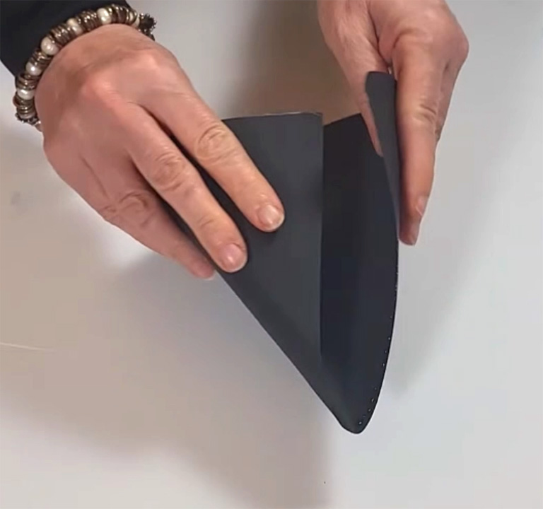 Folding a black hat piece into shape for DIY graduation party decor.