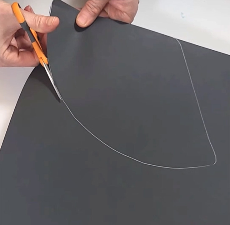 Cutting out a curved hat piece for DIY graduation party decor.