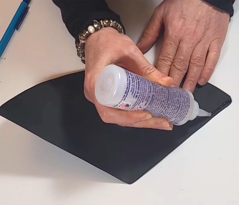 Applying glue to a black hat piece for DIY graduation party decor.