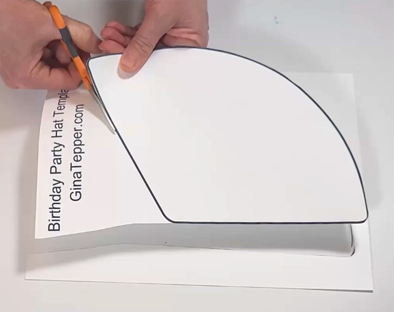 Cutting out a graduation party hat template with scissors