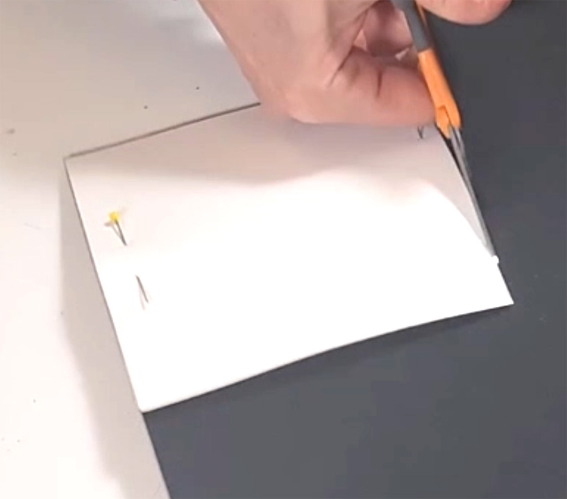 Cutting white paper tassel pieces for DIY graduation party decor.