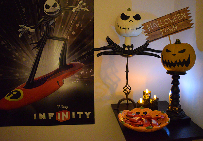 DIY Halloween candles staged in a haunted‑house display with Jack Skellington decor, a Halloween Town sign, and pumpkin treats.