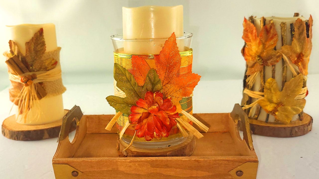 Three DIY fall candles displayed on a painted Dollar Tree wood tray with faux metal accents, creating a rustic autumn centerpiece.
