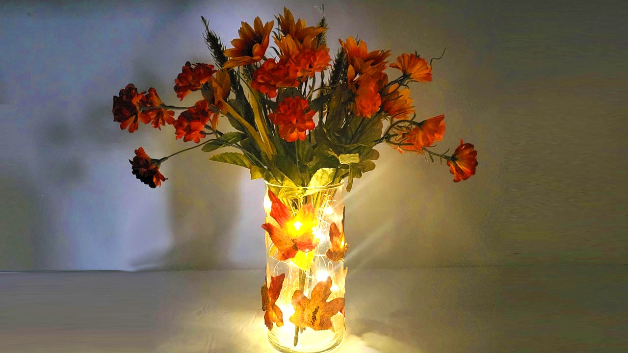 Dollar Tree fall centerpiece with autumn leaves, fall flowers, and glowing fairy lights.