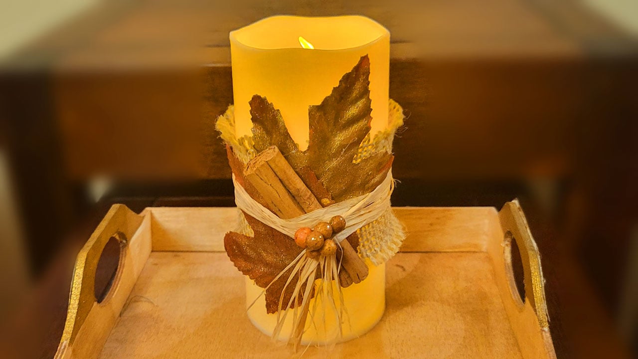 Dollar Tree flameless candle decorated with cinnamon sticks and fall leaves