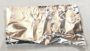 A flat sheet of aluminum foil used as the main tool to clean the burnt residue off a hot glue gun.