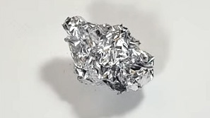 A crumpled ball of aluminum foil used as a safe tool to clean a hot glue gun without scratching the plastic.