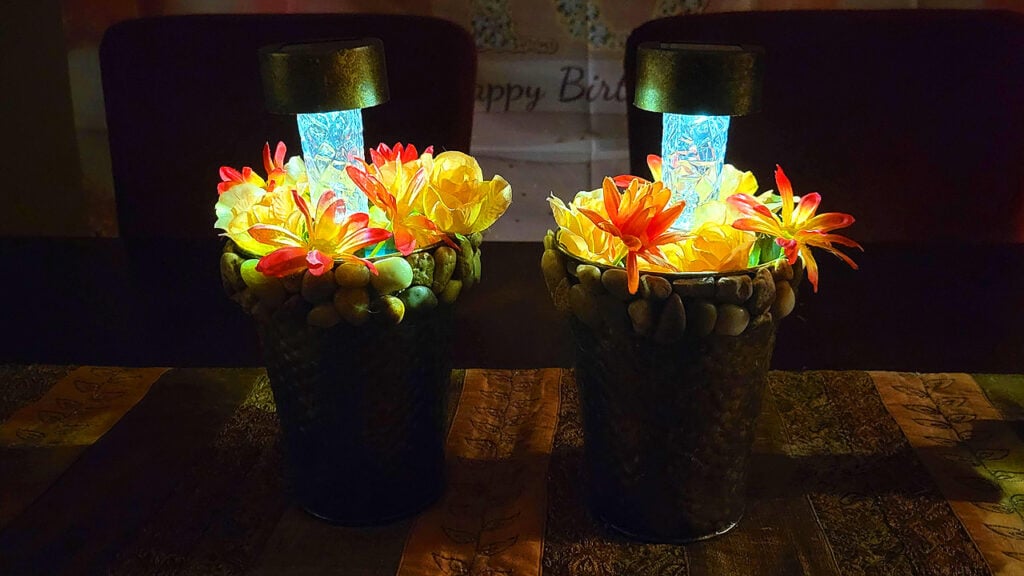 Fall centerpiece with glowing blue solar lights and autumn flowers arranged in metallic vases for seasonal home decor.