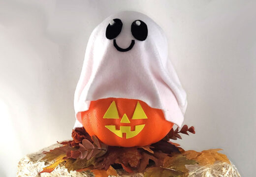Ghost pumpkin craft made from a foam pumpkin covered with white fabric and a smiling ghost face.