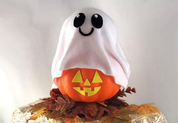 Ghost pumpkin craft made from a foam pumpkin covered with white fabric and a smiling ghost face.