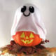 Ghost pumpkin craft made from a foam pumpkin covered with white fabric and a smiling ghost face.
