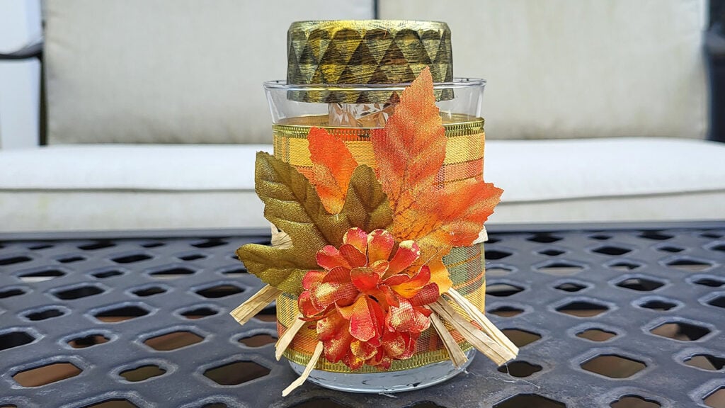 Fall solar lantern decorated with autumn leaves and Dollar Tree supplies, displayed on an outdoor table for seasonal home decor.