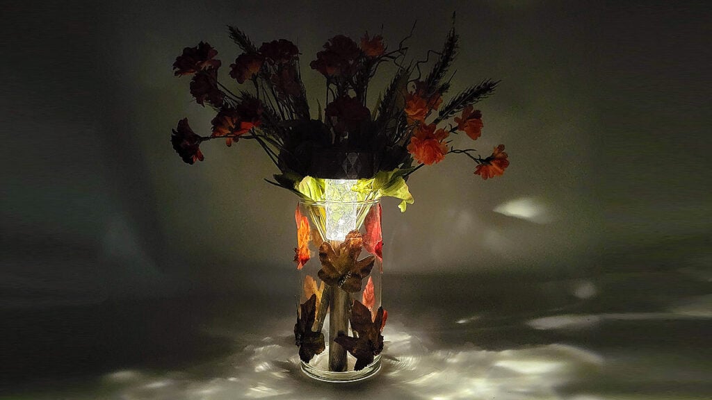 DIY fall solar light display glowing at night with autumn flowers