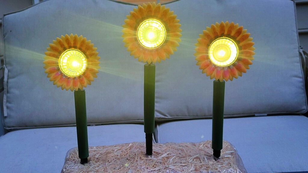 Three sunflower solar lights glowing at night in a DIY outdoor display